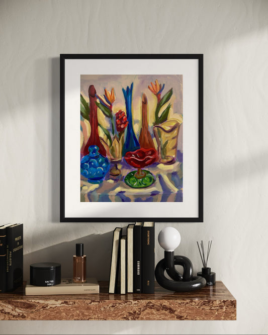 Framed still life painting with colorful vases and tropical flowers displayed on a shelf with books and decorative objects