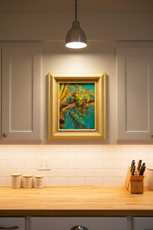 Framed painting of green leaves and blue background held by a hand.