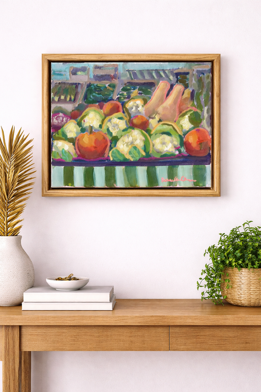 Framed painting of fruits and vegetables on a wall above a wooden console table.