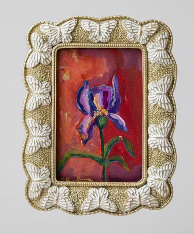 Painting of an iris in a frame held by a hand