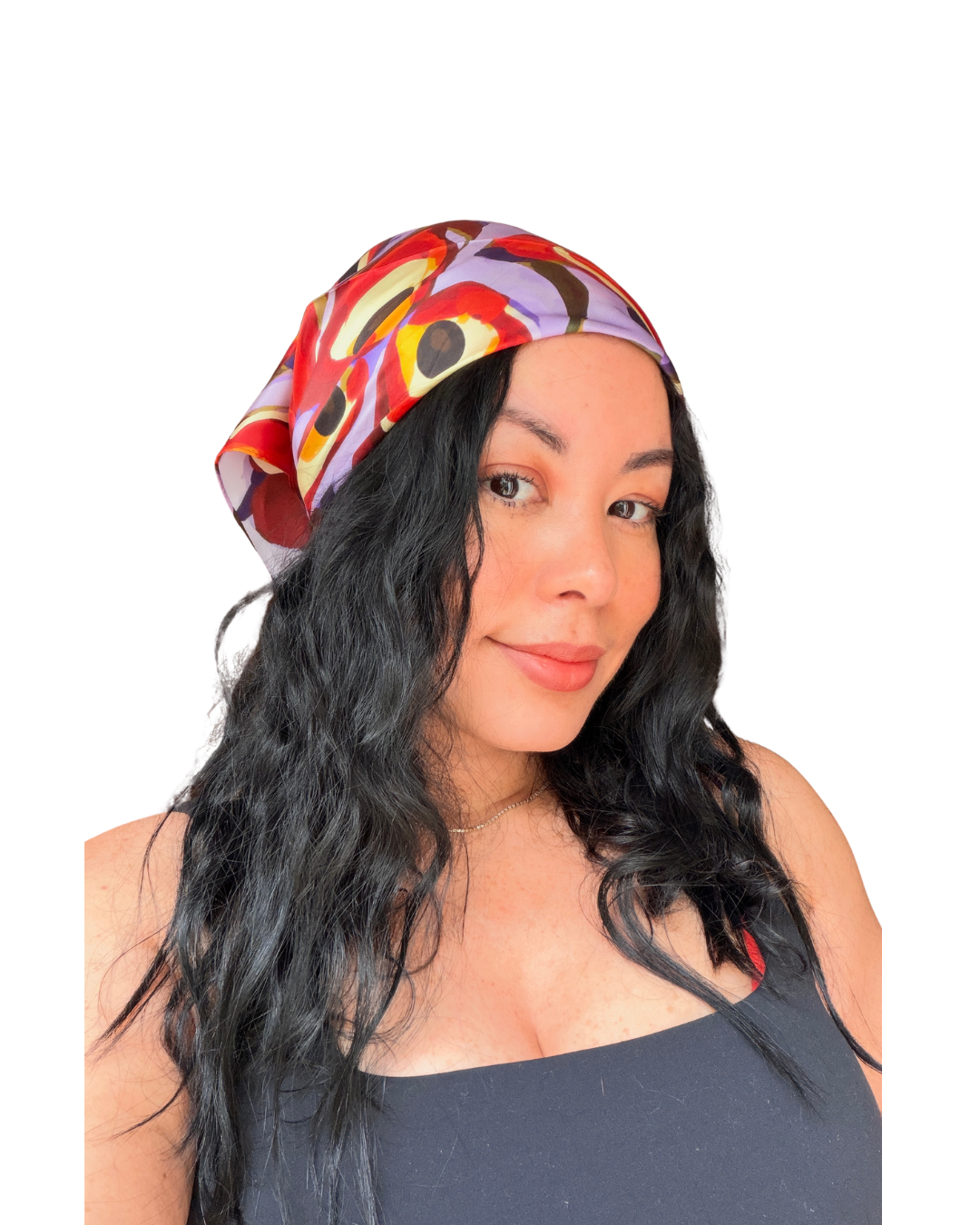 A woman with long, wavy black hair wearing a colorful abstract-patterned headscarf and a dark gray top, photographed against a solid white background.