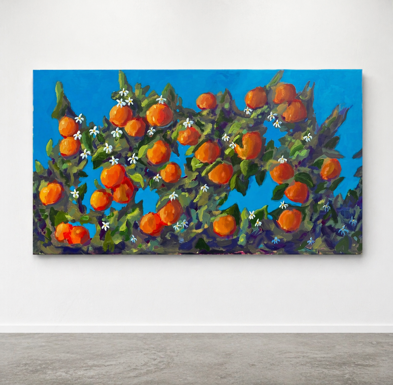 Painting of oranges on a branch with flowers against a blue sky on a white wall.