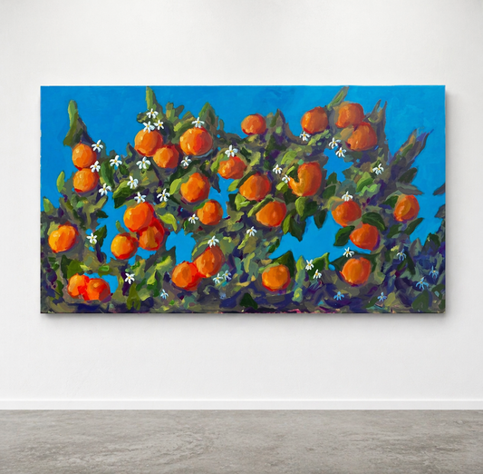 Painting of oranges on a branch with flowers against a blue sky on a white wall.