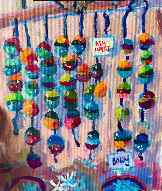 Colorful artwork of fishing buoys held by a hand with red nail polish.
