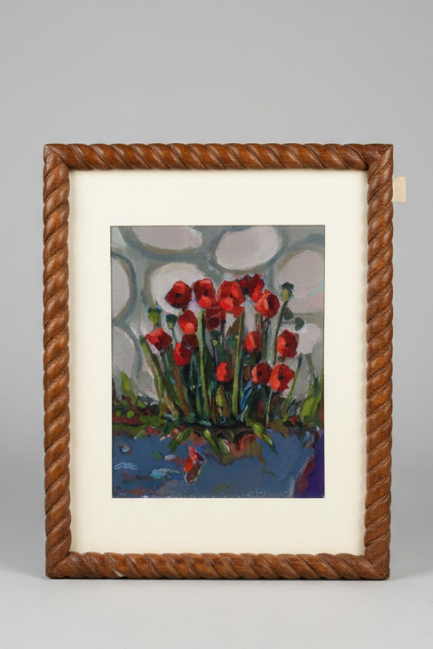Framed painting of red flowers with a rope-like border on a table.