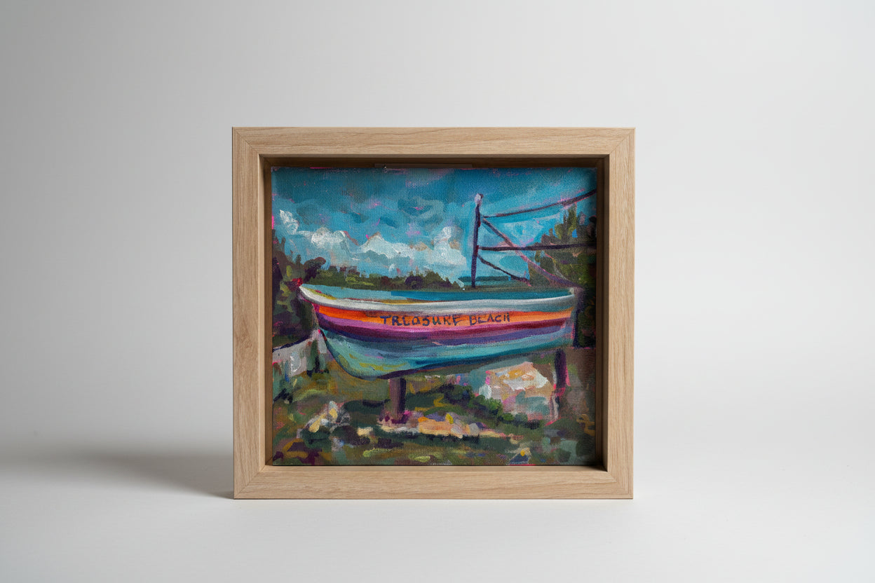Framed painting of a boat with 'Trebuchet Beach' text, held by a hand.