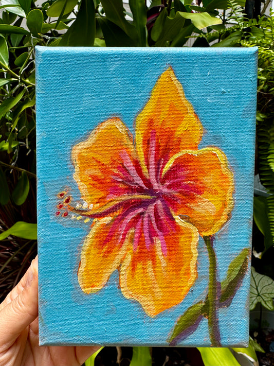 Painting of a yellow flower on a blue background held in front of green foliage.
