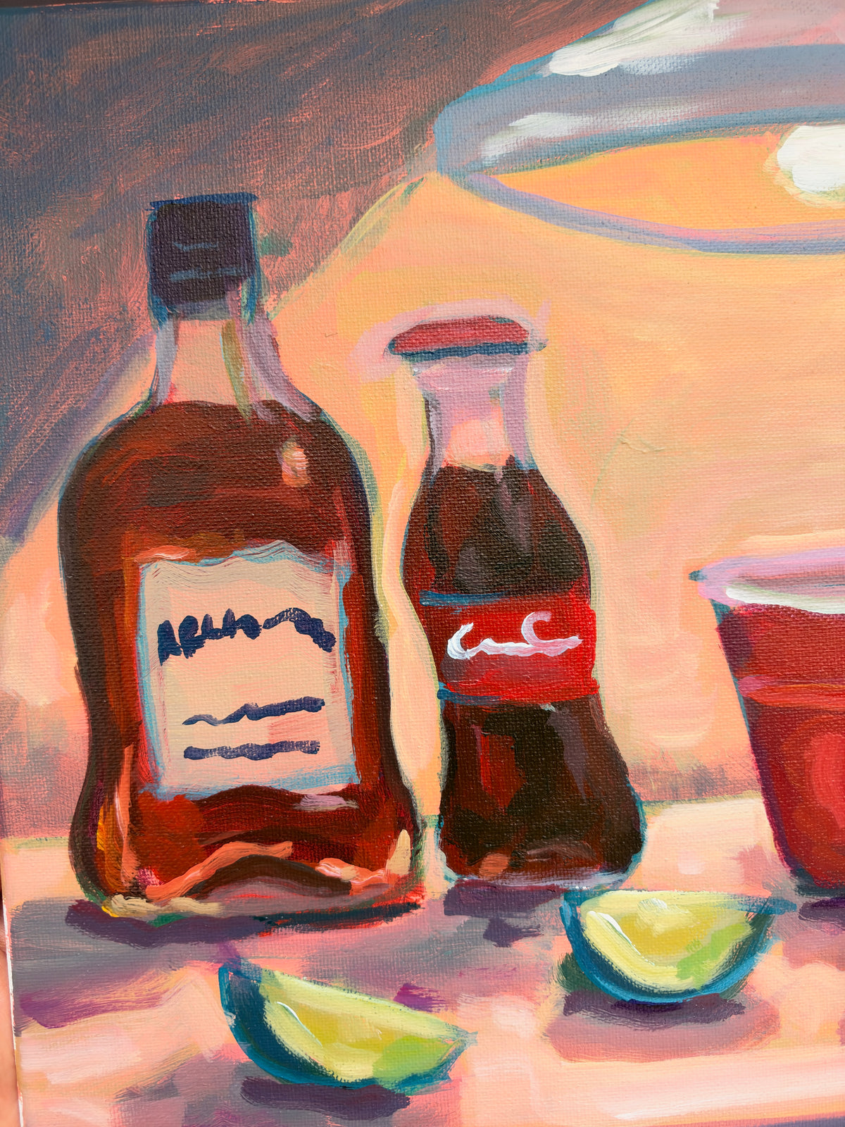 A colorful painted still life showing two dark bottles, a red cup, and lime wedges on a warm-toned surface with a blurred bowl in the background.