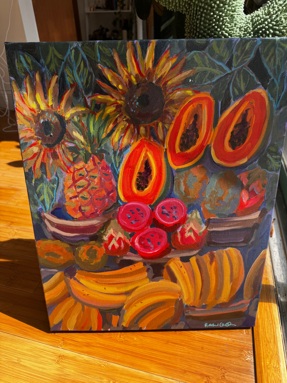 An expressive oil painting of a fruit still life featuring sunflowers, papayas, pineapple, dragon fruit, strawberries, and bananas, displayed on a wooden table.