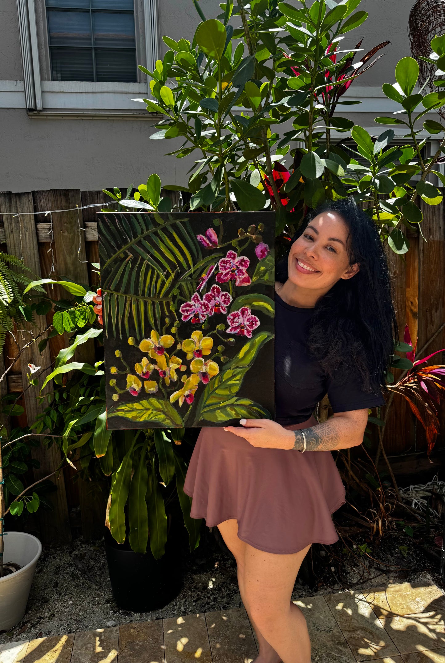 Woman holding a painting of flowers in a garden setting