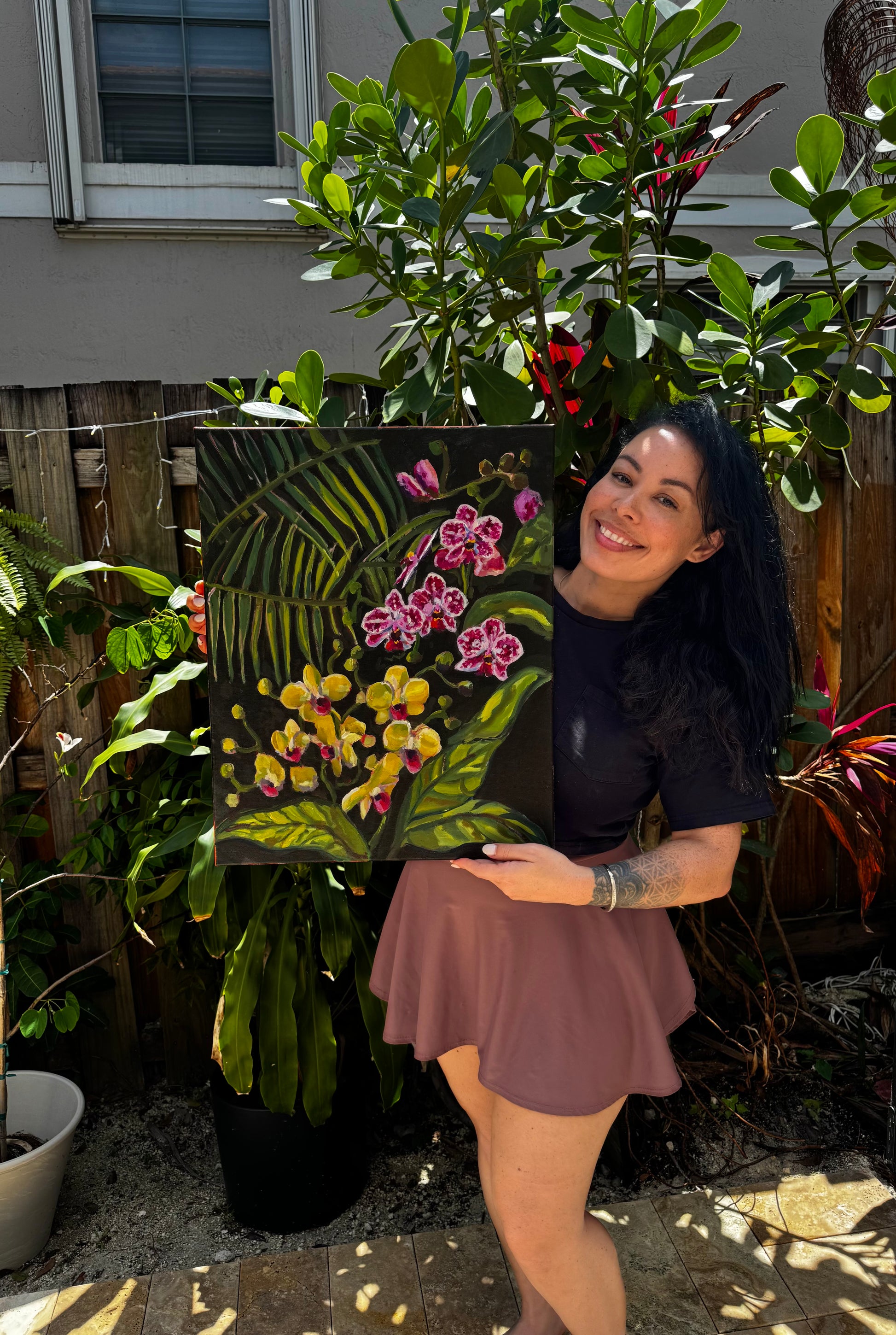 Woman holding a painting of flowers in a garden setting