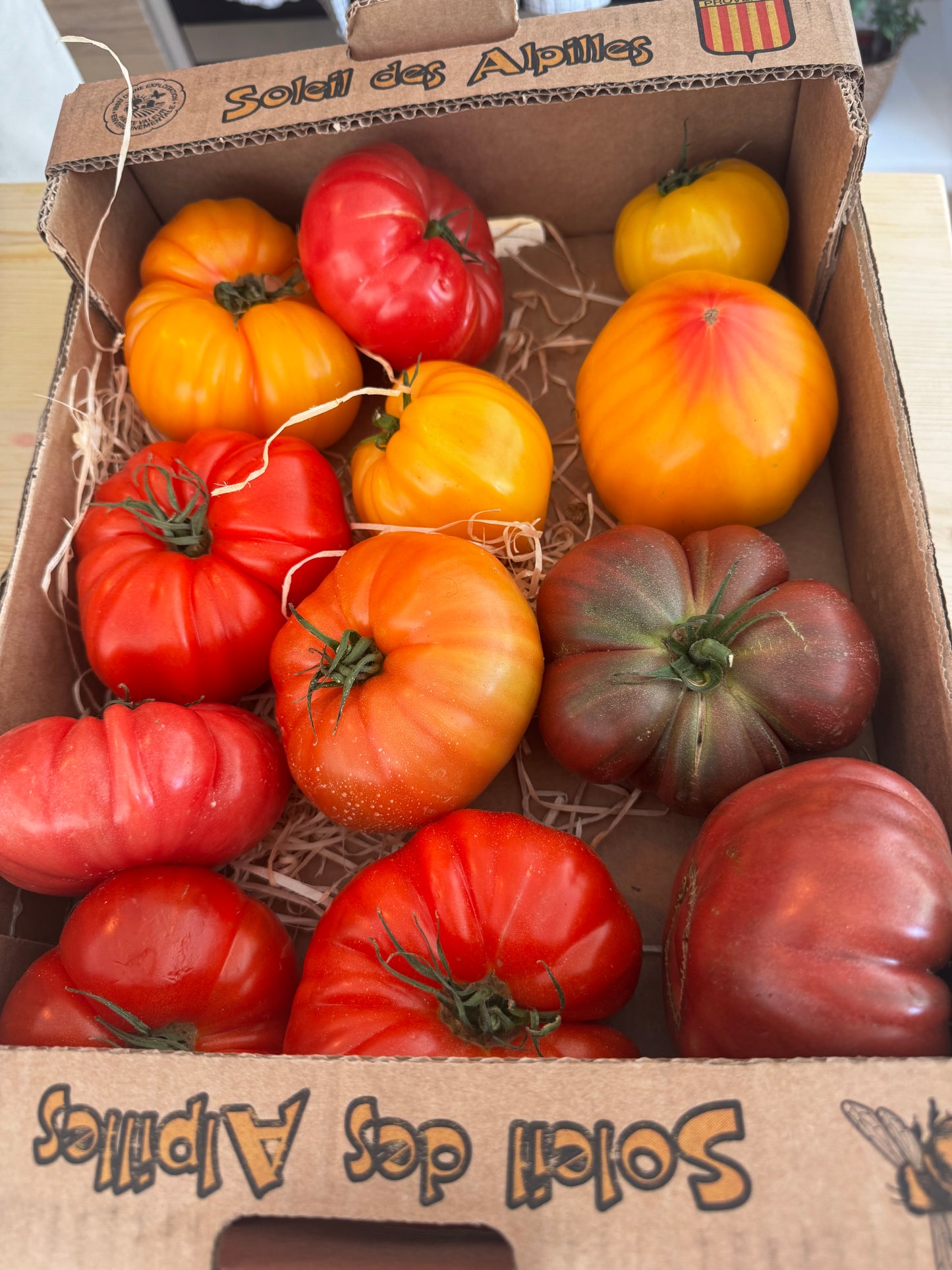 Assorted tomatoes in a cardboard box labeled 'Soleil des Alpes'.