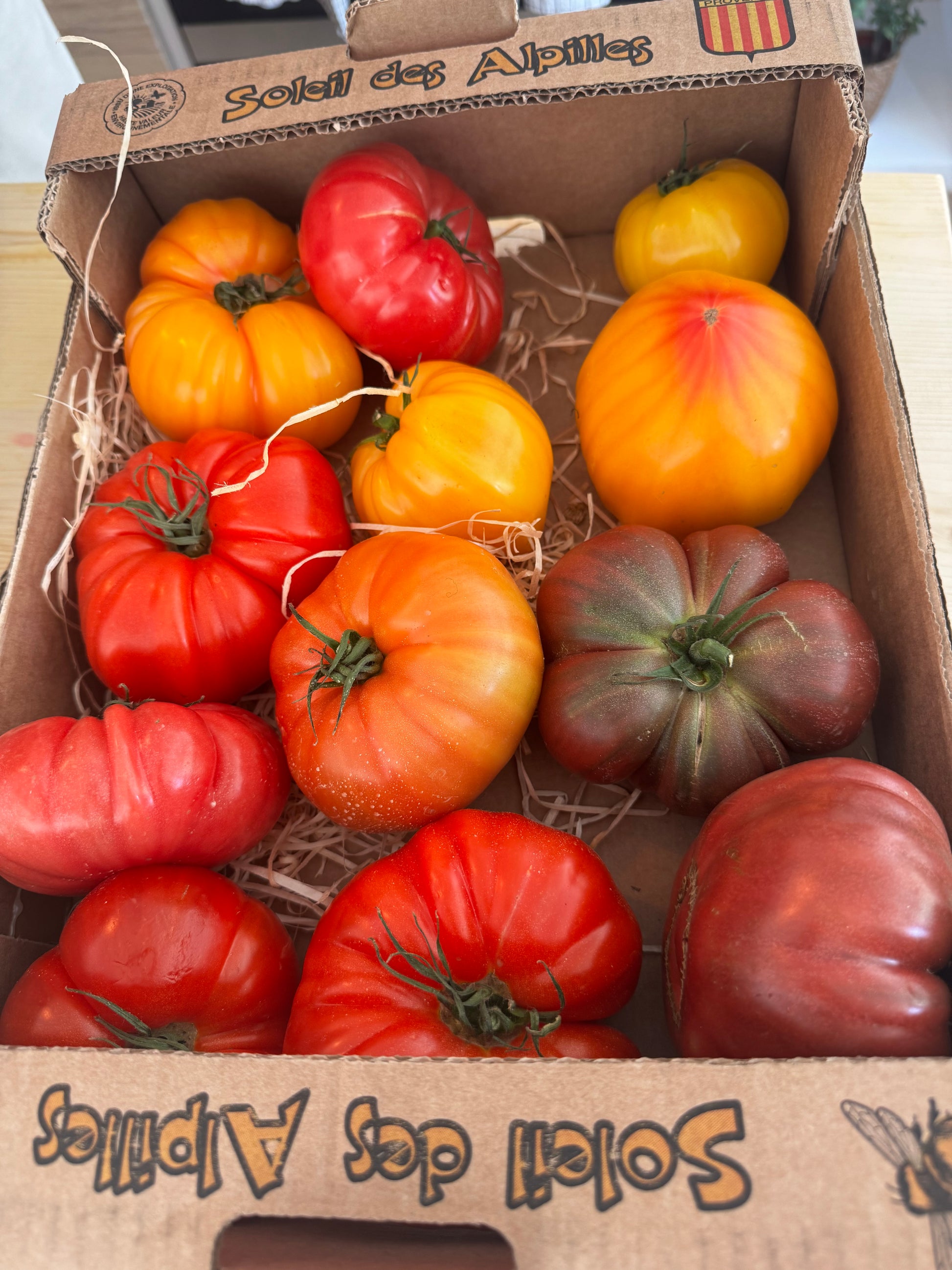 Assorted tomatoes in a cardboard box labeled 'Soleil des Alpes'.