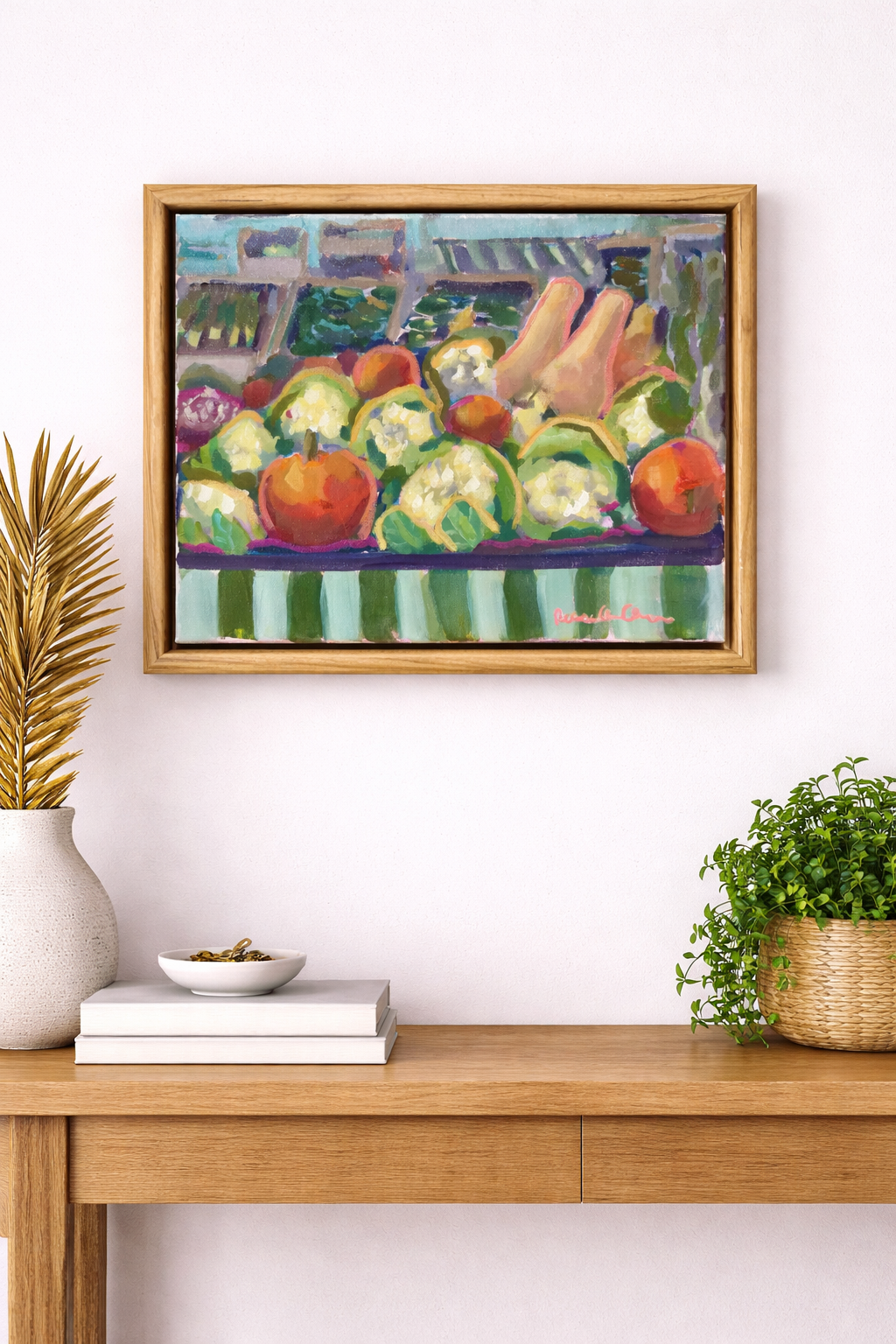 Framed painting of fruits and vegetables on a wall above a wooden console table.