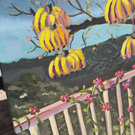 Video of painting with bananas and pineapple hanging on a balcony overlooking mountains. 